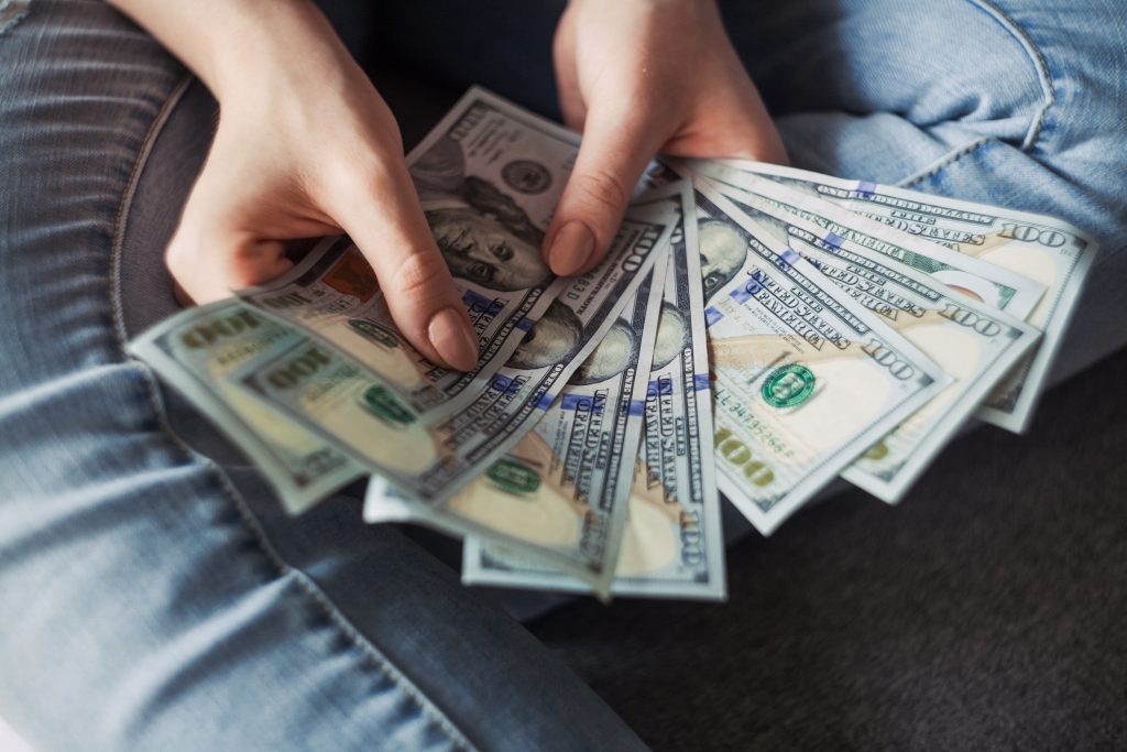Unidentified woman holding a was of cash | Image: Unsplash