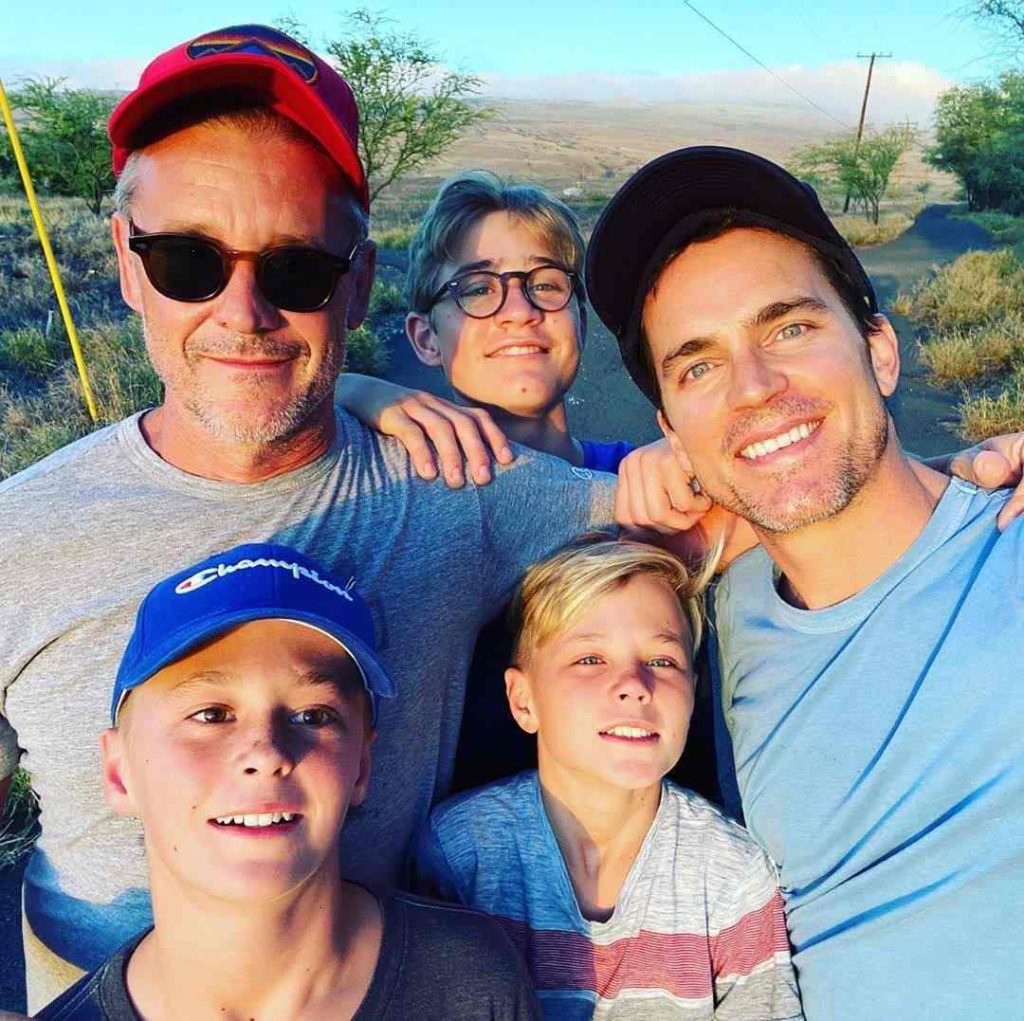 A picture of Simon Halls with his husband, and their kids.
