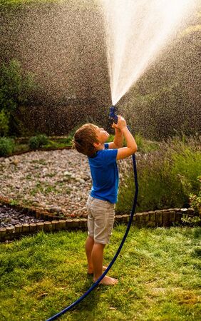A child playing with a garden hose