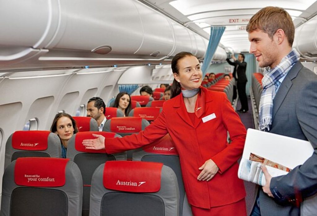 An image of a flight attendant directing a passenger to his seat
