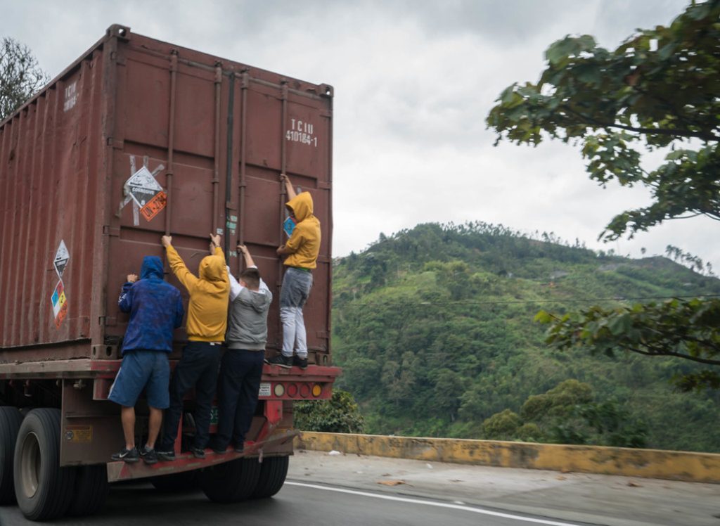 Migrants hanging on the back of a truck