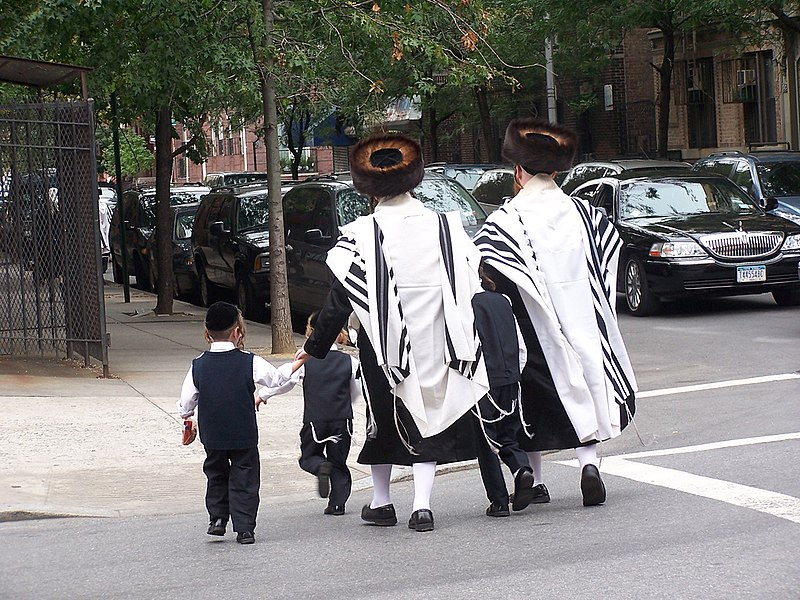 Two Jewish men and some kids walking through Brooklyn