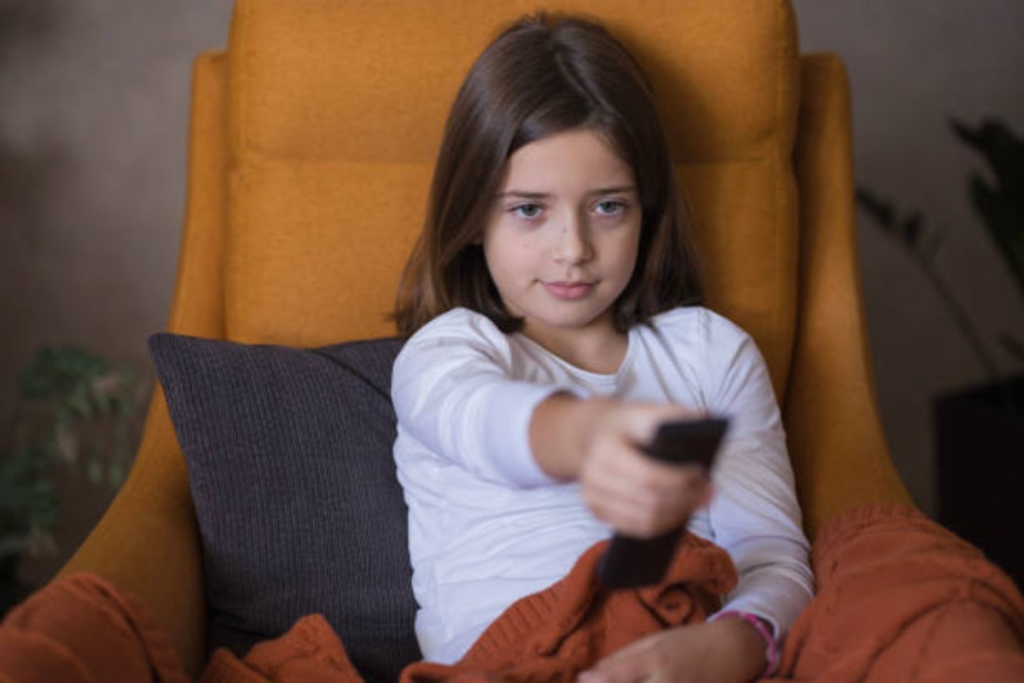 Tiny girl on the couch holding a remote control while curled up on the couch