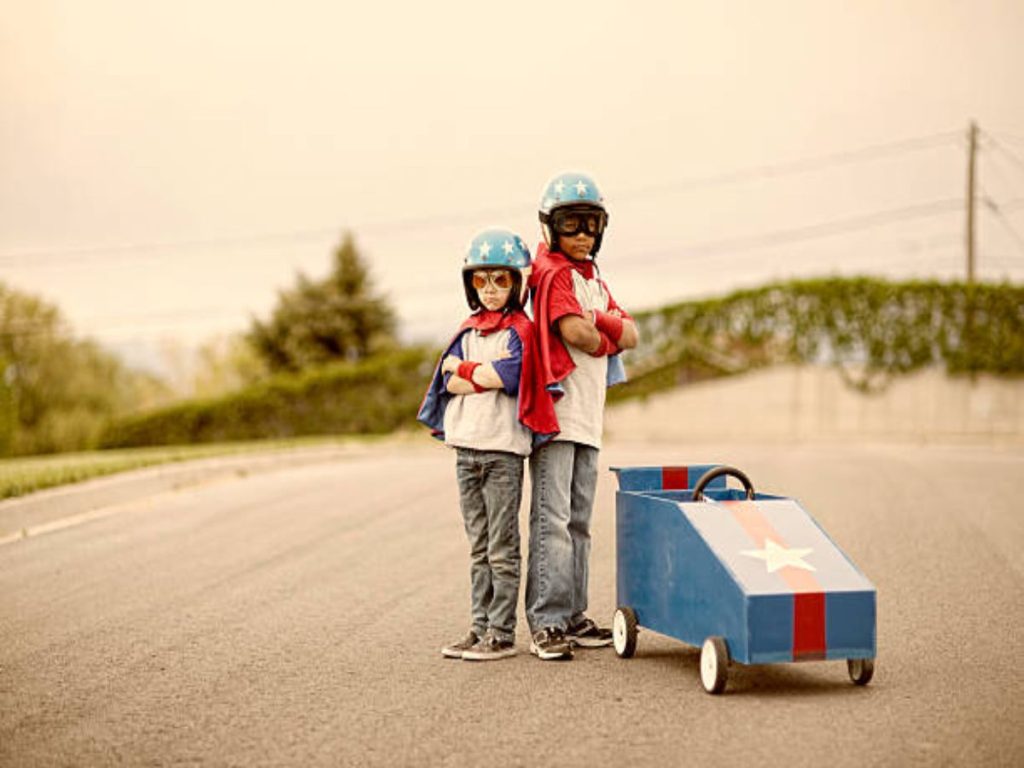 Two young boy racers next to their racing boxcar, ready for speed.