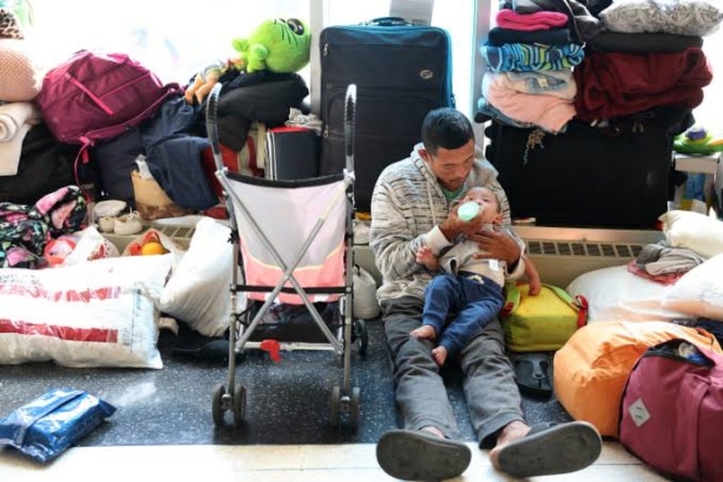 Man feeding his child at a migrant shelter