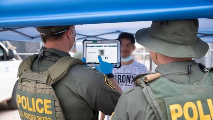 Two border patrol officers documenting a migrant