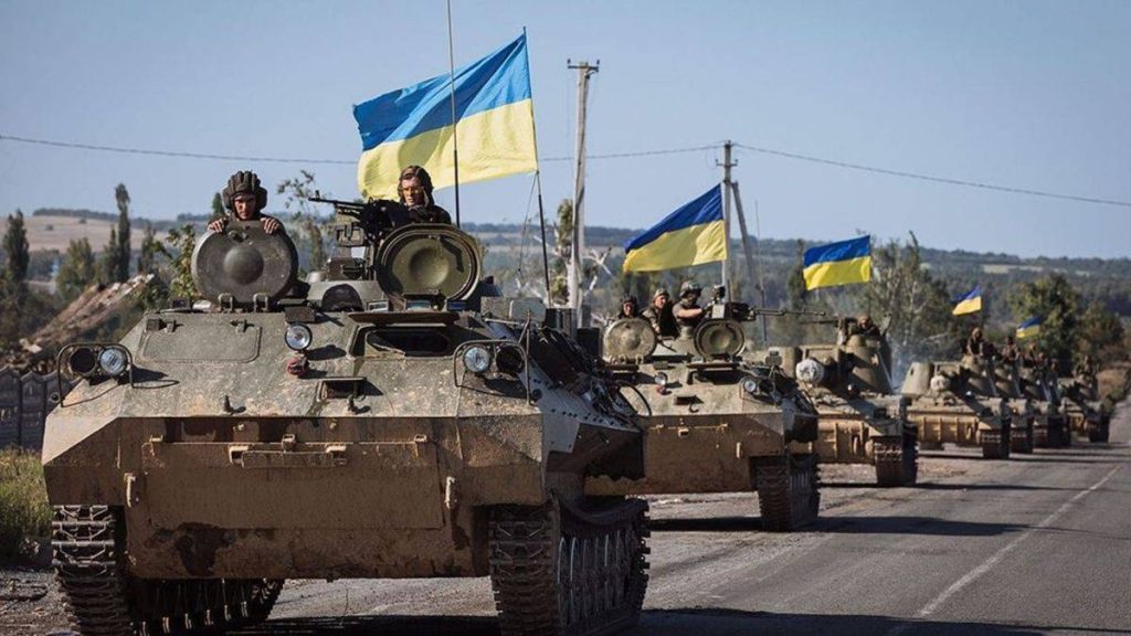 Several Ukrainian tanks driving down a road