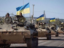 Several Ukrainian tanks driving down a road