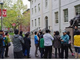 Students standing around the statue of John Harvard