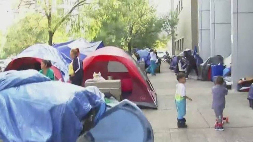 Kids playing around tents on a street curb