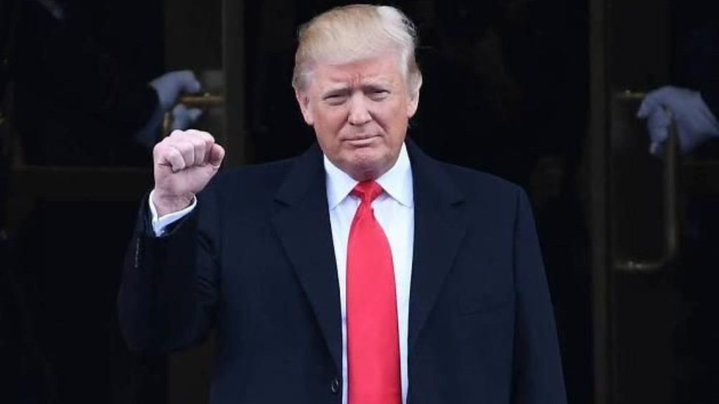 Donald Trump standing outside a building with a fist raised