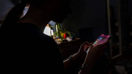 A young lady surfing the internet in a sparsely lit room