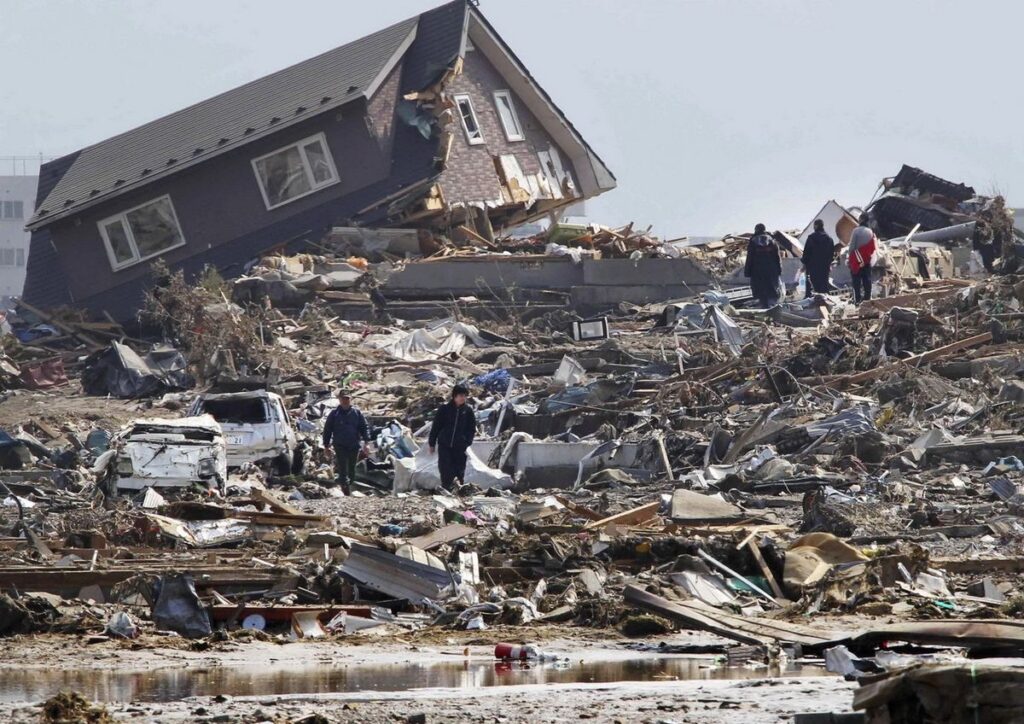 People walking through the wreckage caused by a natural disaster