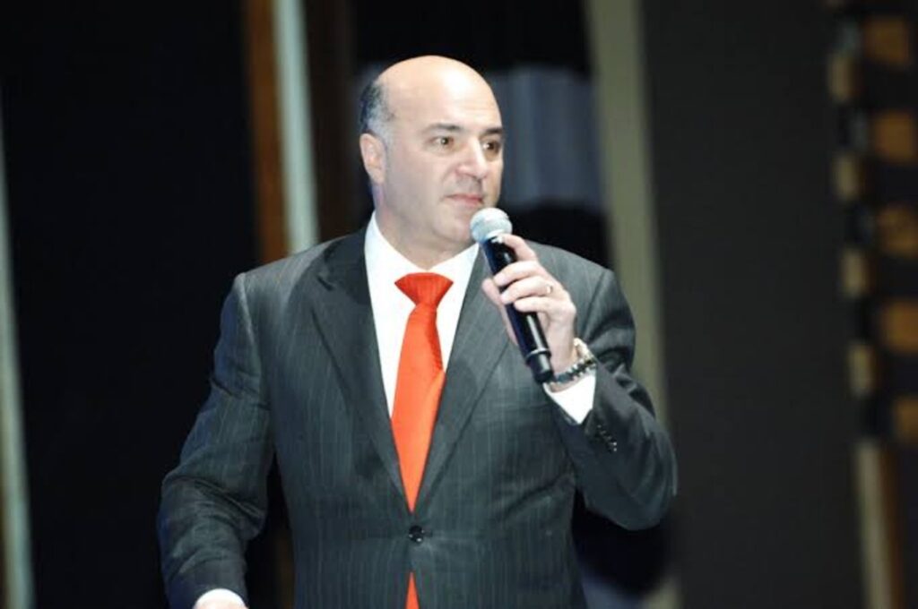 O'Leary speaking at an event, mic in hand