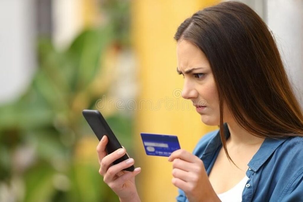 A Woman Holding a Cell Phone and a Credit Card