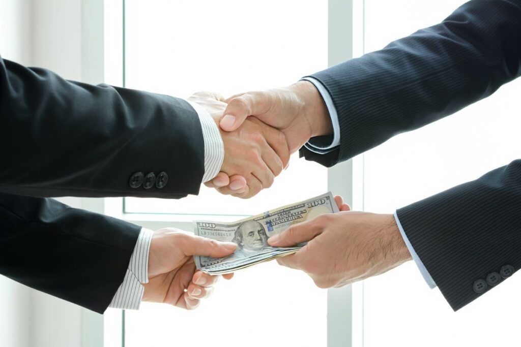 Two people shaking hands and exchanging money.