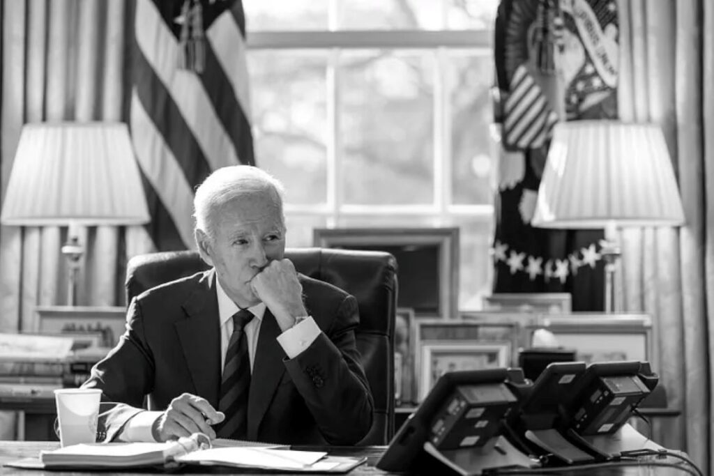 Biden sitting thoughtfully in the Oval Office