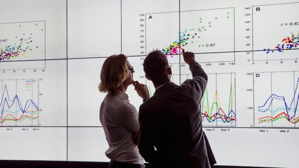 Two people looking at multiple graphs.