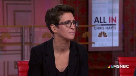 Rachel Maddow sitting in a studio listening to a collegue