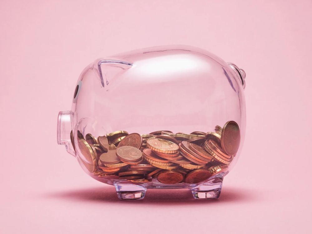 a transparent piggy bank with some coins in it.