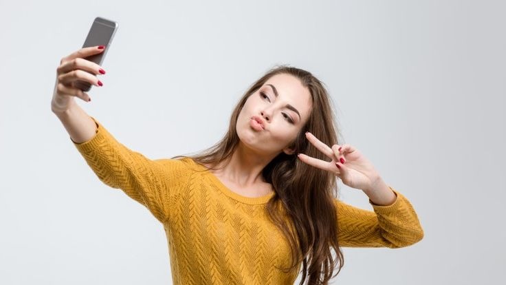 A woman taking a selfie while making the peace sign