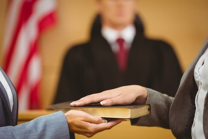 A person swearing on the bible in a law court