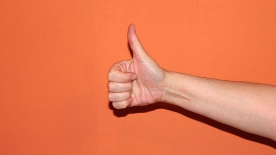 A thumbs up sign set against an orange background