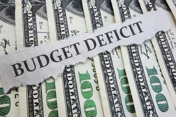 Budget deficit written on a piece of paper placed ontop of a row of $100 notes