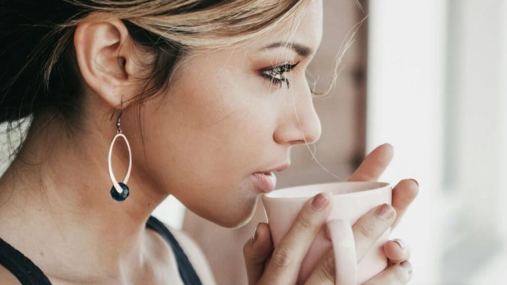 A woman drinking from a mug.