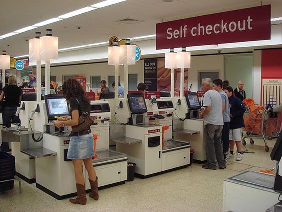Customers in the self checkout section of a store