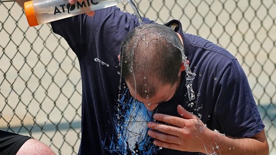 A man dousing himself with water from a bottle