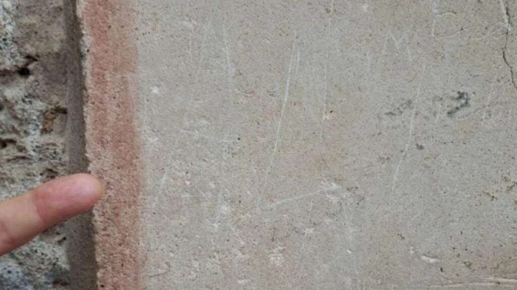 A tourist carving of a name on an ancient Pompeii wall.