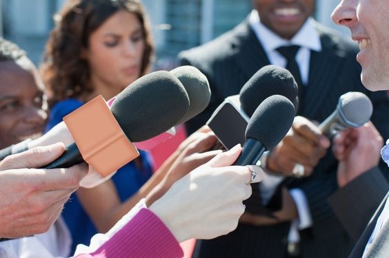 A man speaking into mics held by reporters