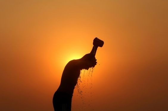 Silhoutte of a man dousing himself with water set against a fiery background