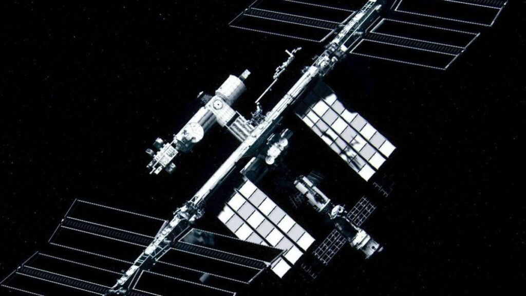 A silver space station floats in space set against a black background. Various antennas and metal panels are seen