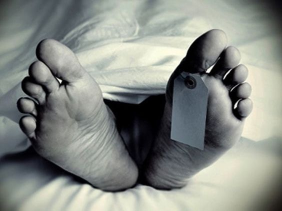 A black and white shot of a dead body with a toe tag