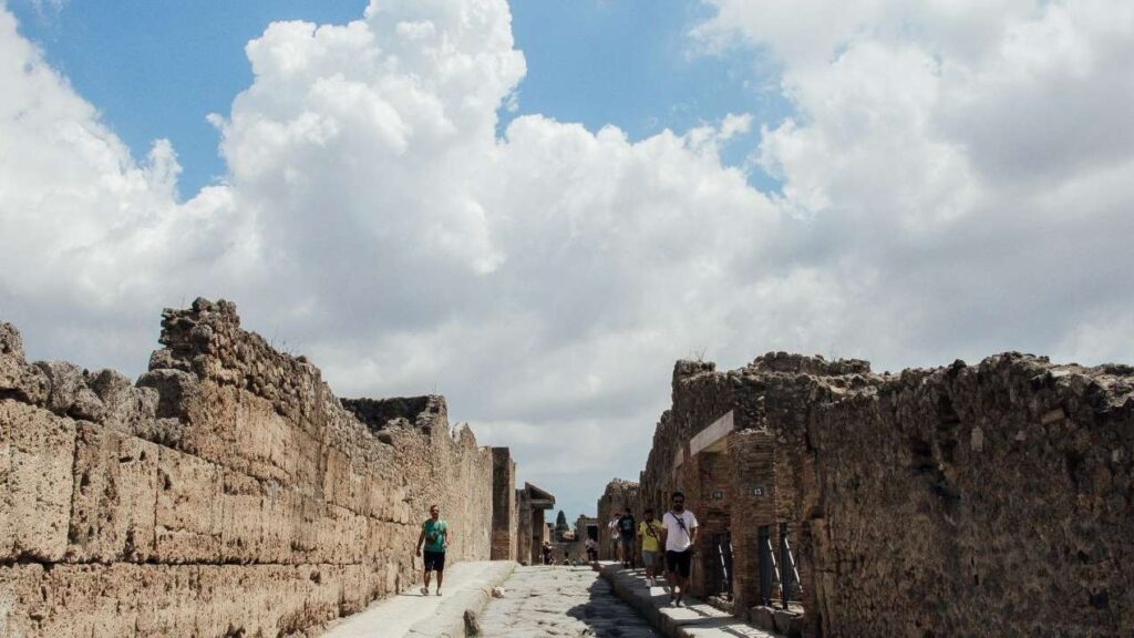 People walking around the ancient ruins of Pompeii’s streets.