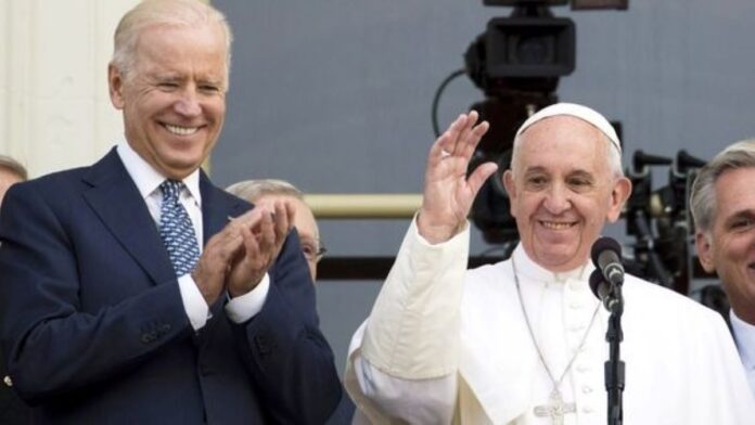 Pope Francis and President Biden standing side by side wearing happy smiles