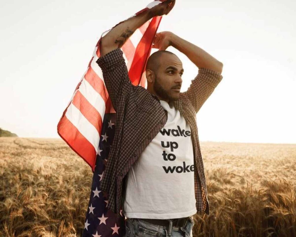 A man wearing a "Wake up to woke" shirt holding a US flag