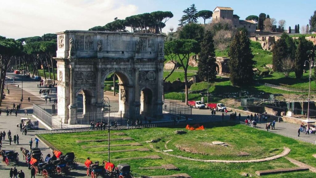 An aerial view of many tourists walking around Italy’s Arch of Constantine.