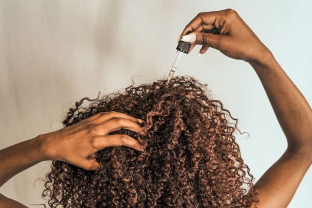 A picture of a woman applying hair growth oil.