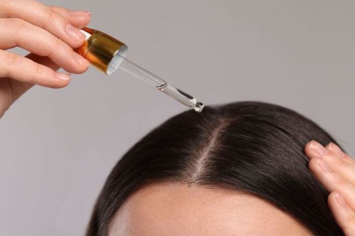 A picture of a woman applying hair growth oil