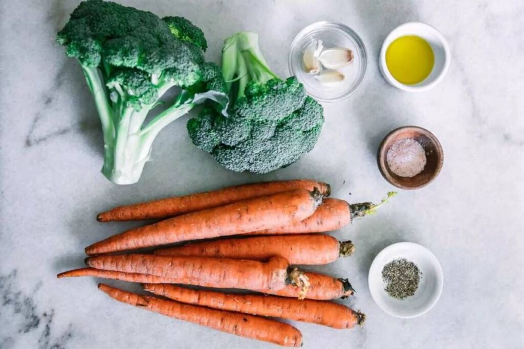 A picture of some carrots and broccoli and spices.