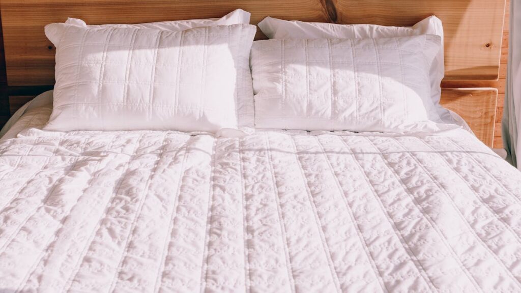 A mattress with white sheets and pillows on it
