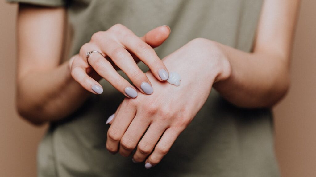 Crop woman applying cream on hands
