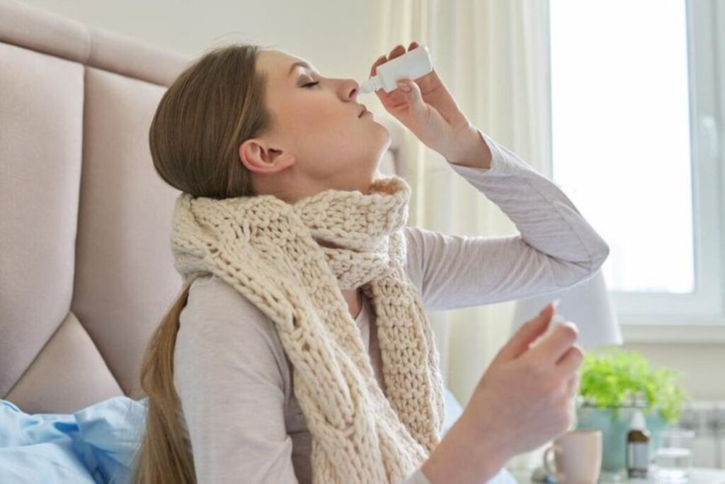 A picture of a woman using a nasal spray