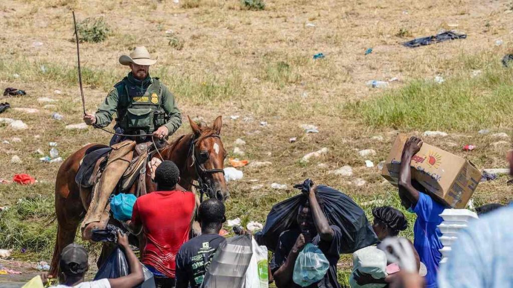 A border patrol officer interacting with haitian migrants